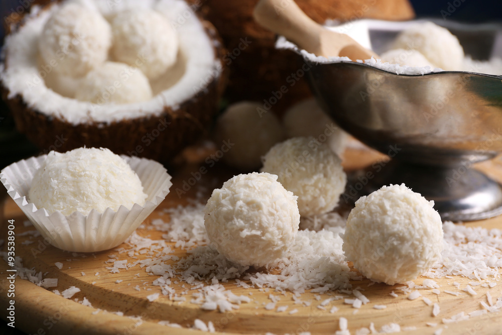 Candies in coconut flakes and fresh coconut on wooden board, close-up Candies in coconut flakes and fresh coconut on wooden board, close-up