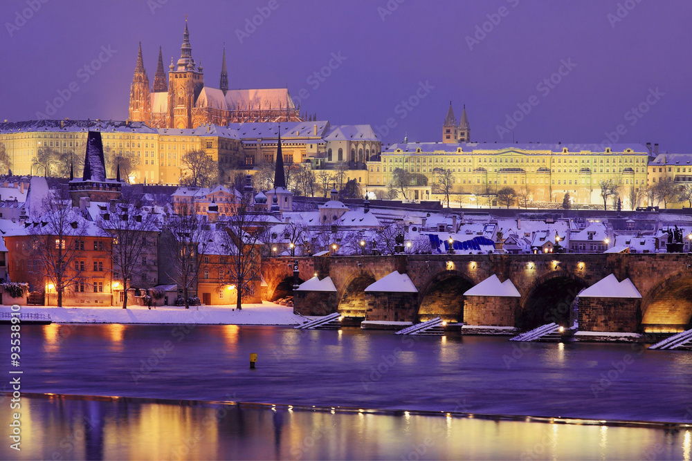 Fototapeta premium Night snowy Prague gothic Castle and St. Nicholas' Cathedral with Charles Bridge, Czech republic