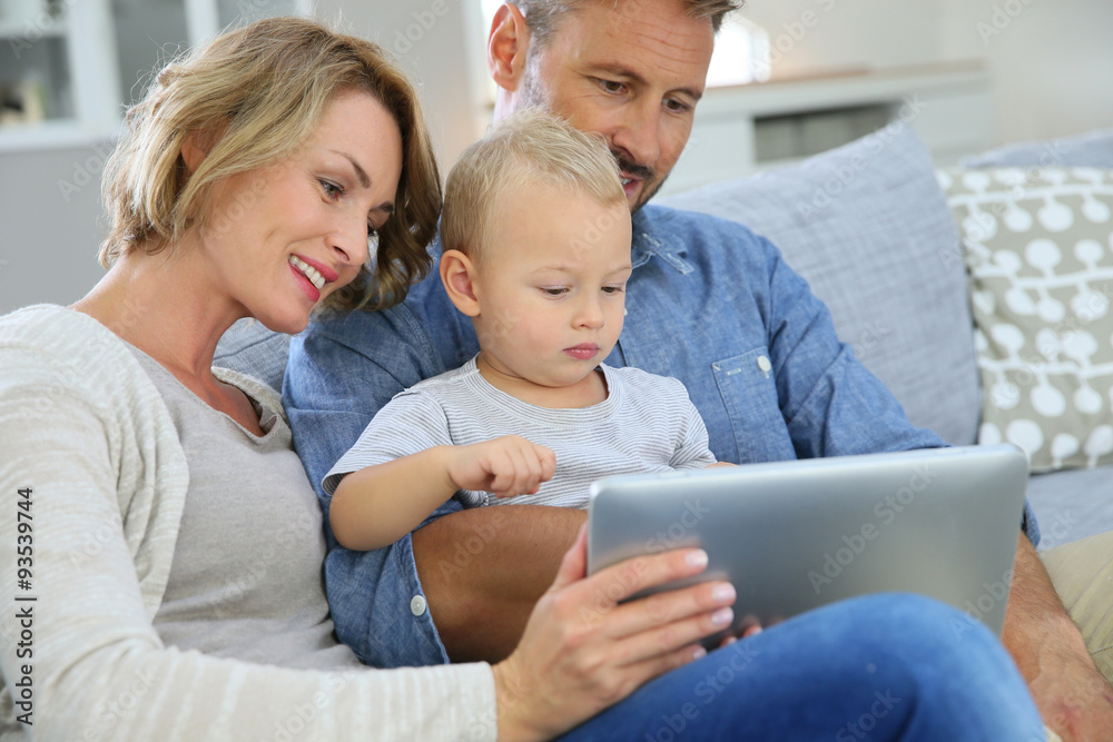 Parents with baby boy playing with digital tablet