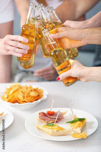 Friends hands with bottles of beer and snacks , close up