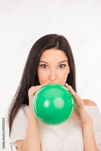 funny girl inflating a green balloon