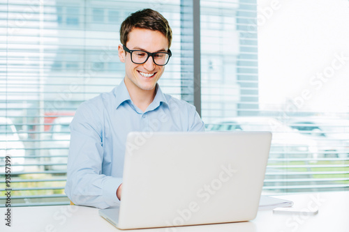 Happy young man typing on laptop