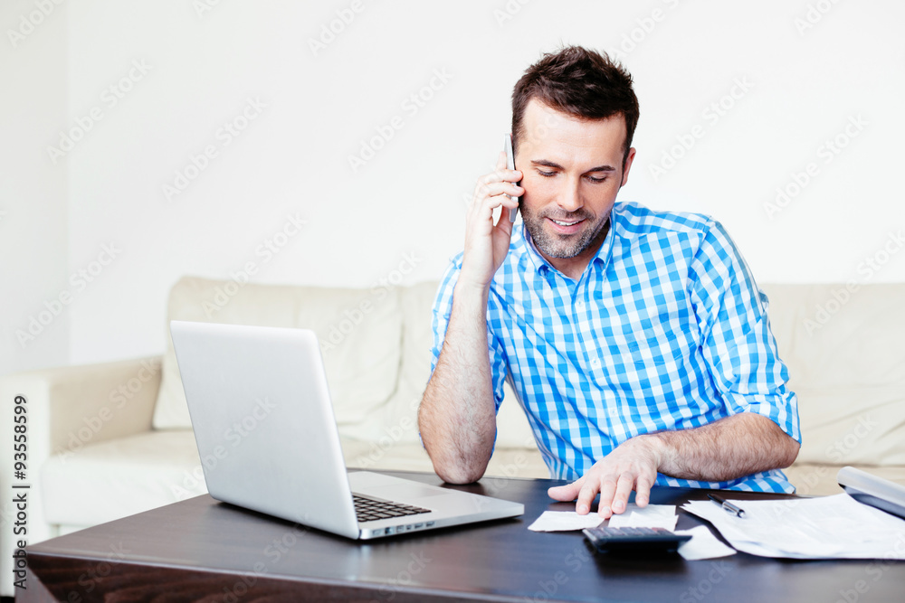 Handsome man comparing two receipts and talking on a mobile Handsome man comparing two receipts and talking on a mobile