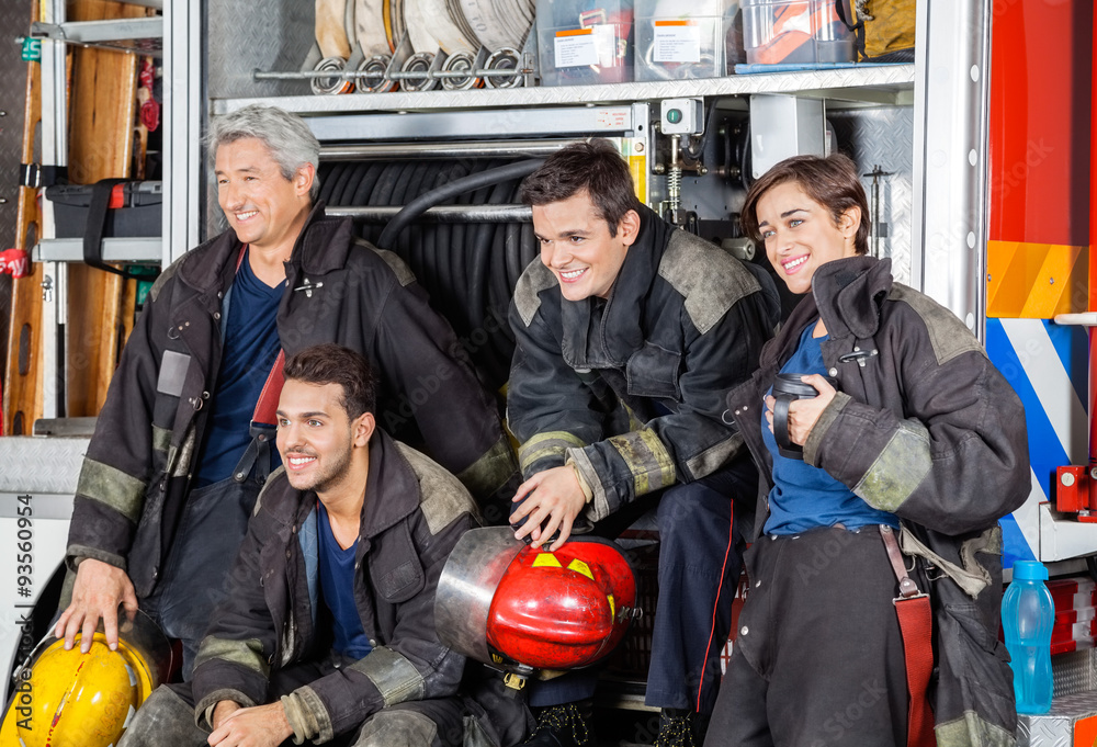 Naklejka premium Team Of Happy Firefighters By Firetruck