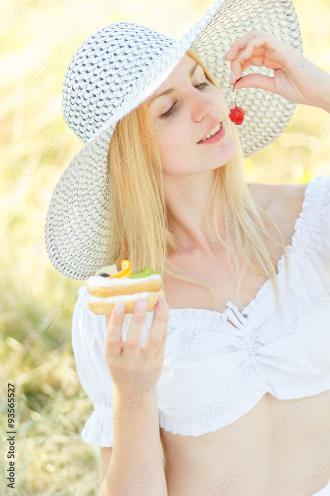 Young pretty blonde fashion girl sensual portrait posing outdoor in summer eating cake with fruits Young pretty blonde fashion girl sensual portrait posing outdoor in summer eating cake with fruits