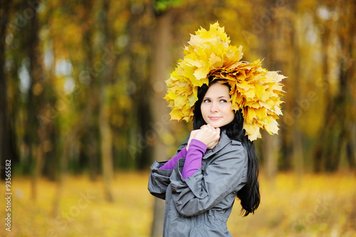 beautiful girl with a wreath of yellow leaves on the head on a b