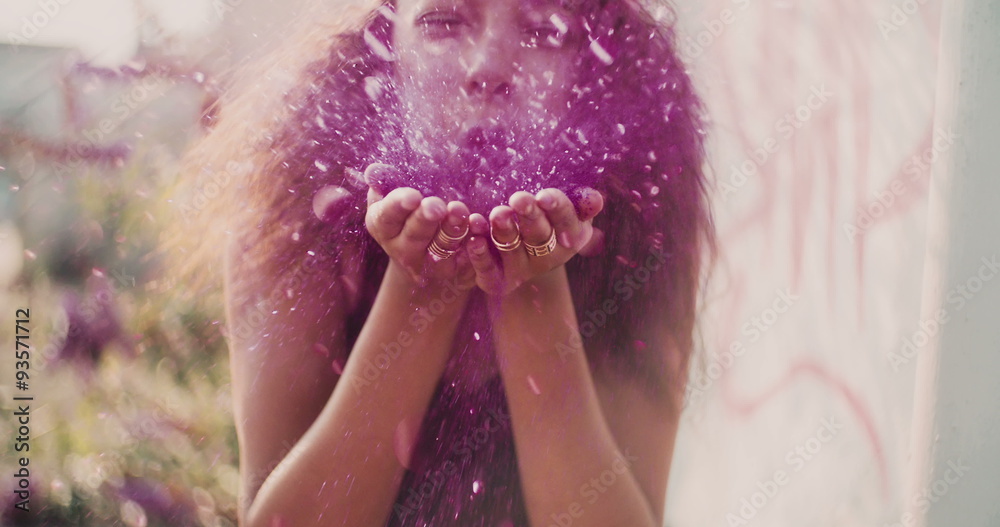 Bright pink glitter being blown by a teenage girl