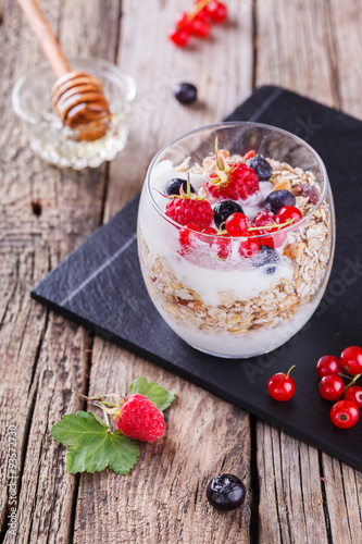 Breakfast with muesli, yogurt,honey and fresh berries in a glass on a wooden background. selective focus