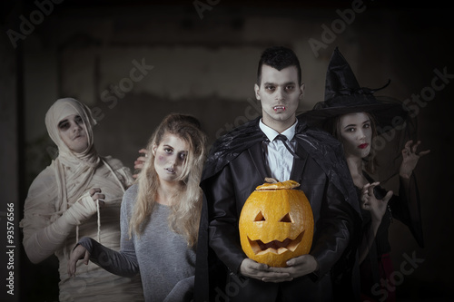 Portrait of a mummy, zombie, witch and a vampire with a carved pumpkin photo
