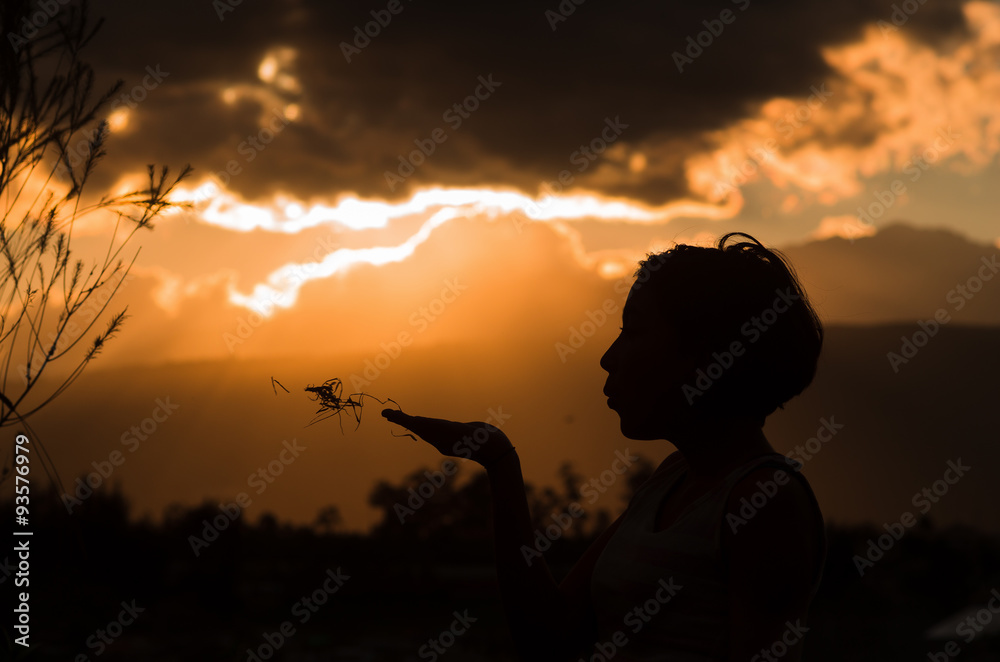 Teenage girl posing with sunset behind clouds in background