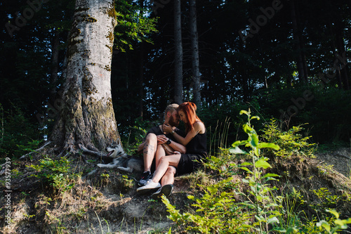 beautiful couple sitting in a forest near the tree