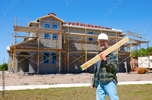 A construction worker contractor in a hard hat is walking through the front of a new house that is under construction