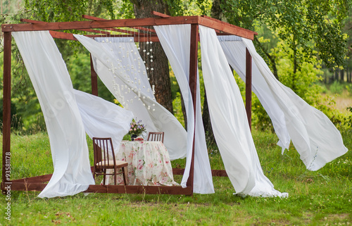 Outdoor gazebo with white curtains. Wedding decorations. Art