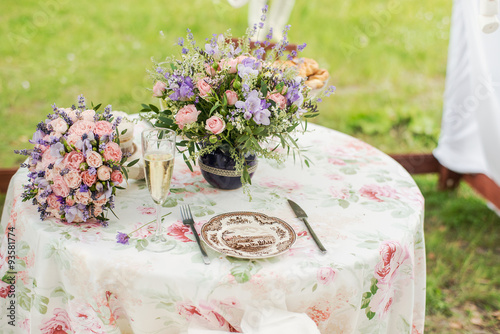 Fototapeta Naklejka Na Ścianę i Meble -  Served table outdoors. Flower arrangement with lavender and