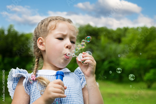 Little girl blowing soap bubbles in park