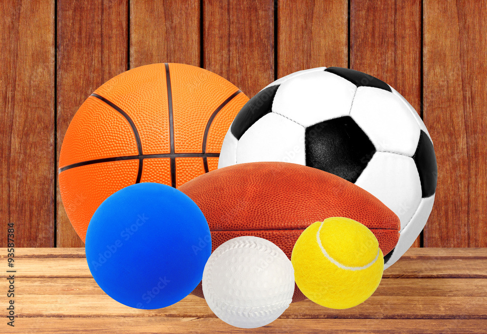 Sports balls on wooden table over wooden planks background