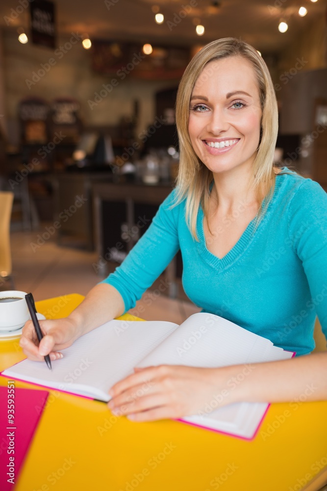 Portrait of happy young woman writing on book