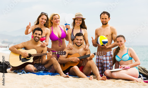 Friends with guitar at beach .
