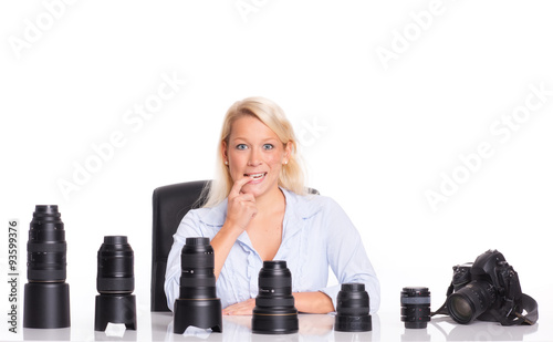 Fotografin sitzt vor verschiedenen Objektiven und überlegt  photo