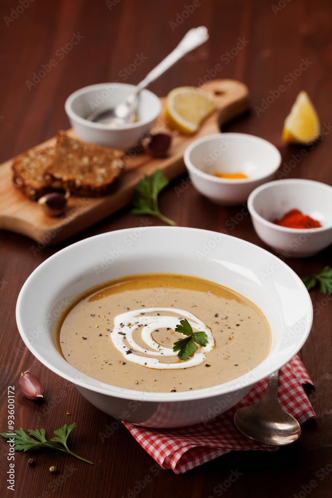 Lentil cream soup in a bowl with spices turmeric, paprika and garlic on wooden table Lentil cream soup in a bowl with spices turmeric, paprika and garlic on wooden table