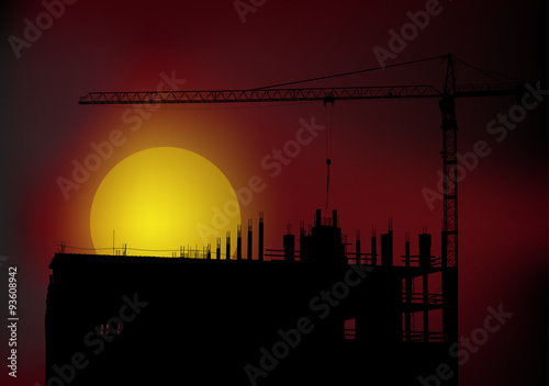 long black crane above unfinished building at sunset