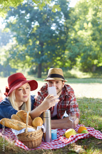 Composite of Couple taking selfie on smartphone on romantic picn photo