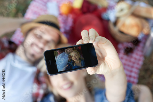 Composite of Couple taking selfie on smartphone on romantic picn photo