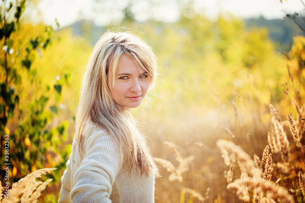Portrait young girl enjoying the beauty of sunny autumn day in high grass in an autumn park. Portrait young girl enjoying the beauty of sunny autumn day in high grass in an autumn park.