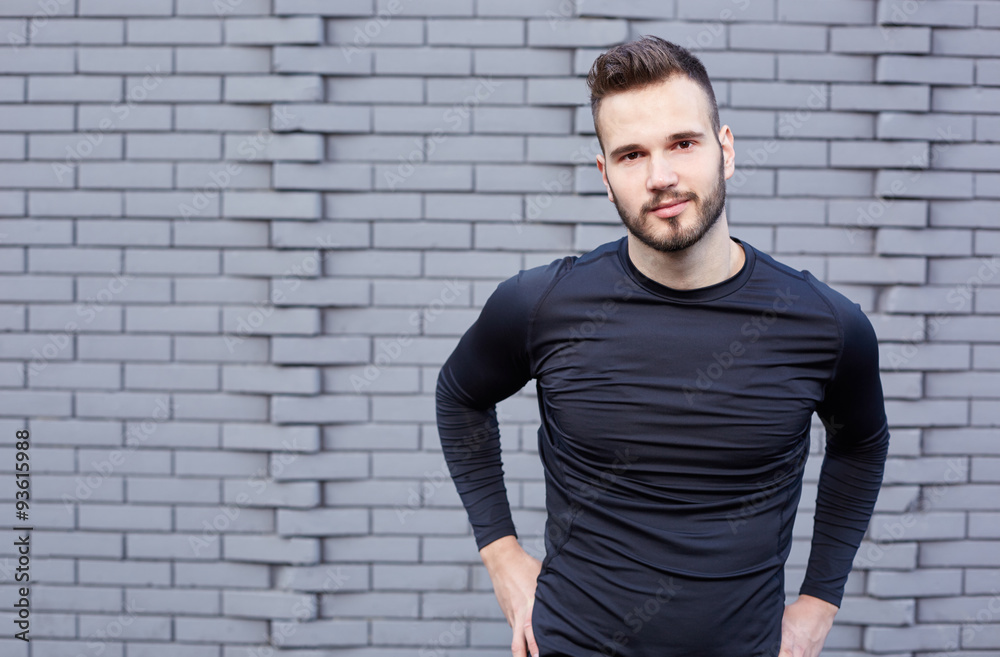 Smiling male runner in t-shirt standing against cement wall background Smiling male runner in t-shirt standing against cement wall background