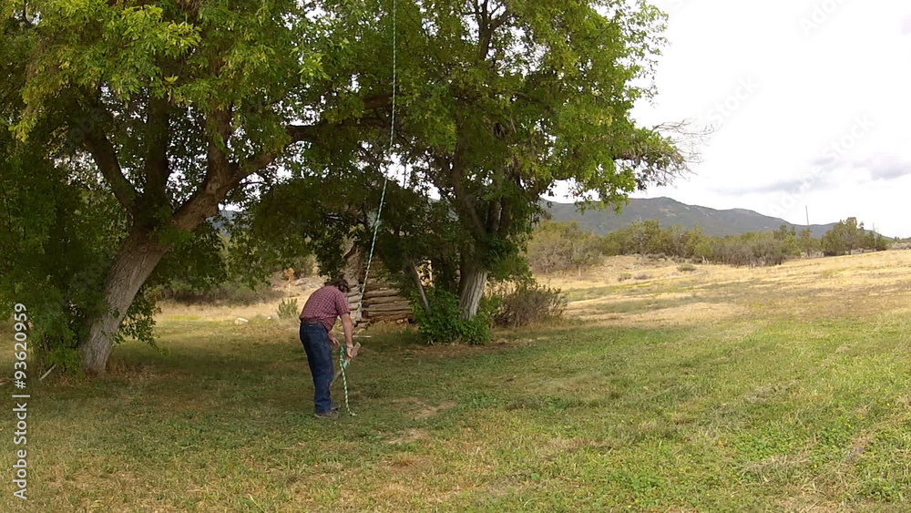 Man swings on children rope swing under rural tree HD 001 Man swings on children rope swing under rural tree HD 001