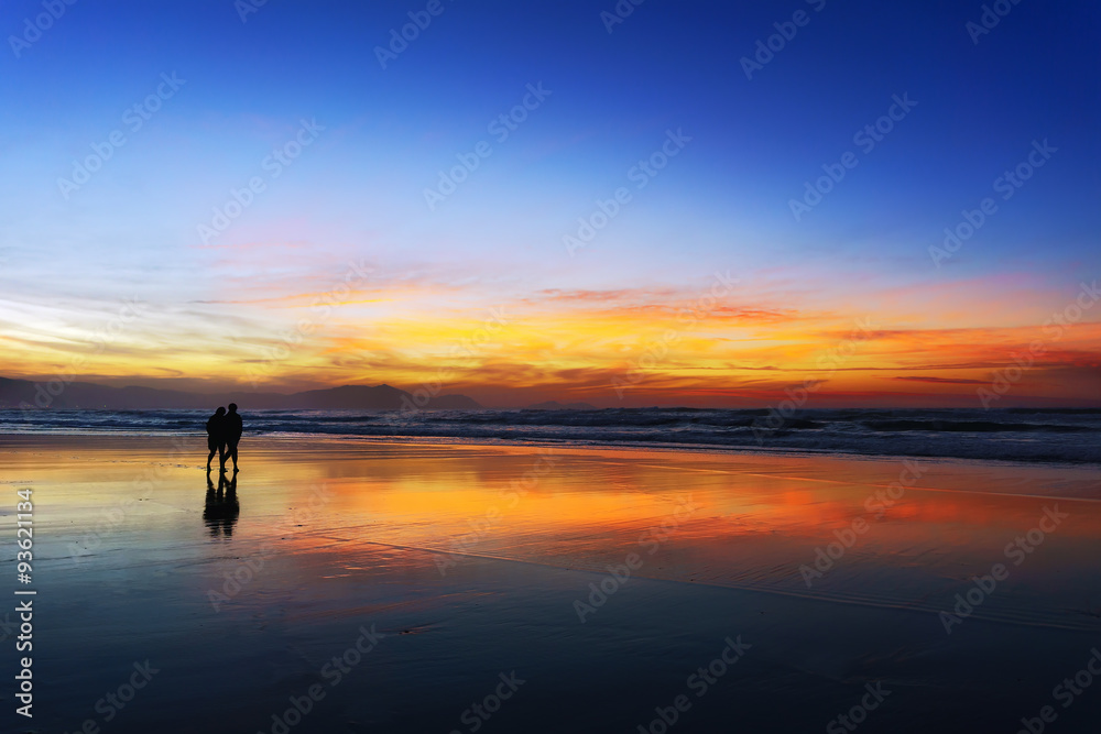 couple walking on beach at sunset