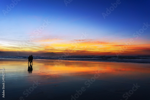 couple walking on beach at sunset © mimadeo