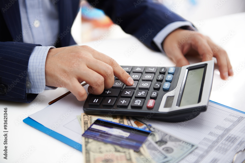 Male economist working on business plan, making calculation of cost and revenue. Paperwork concept. Male economist working on business plan, making calculation of cost and revenue. Paperwork concept.