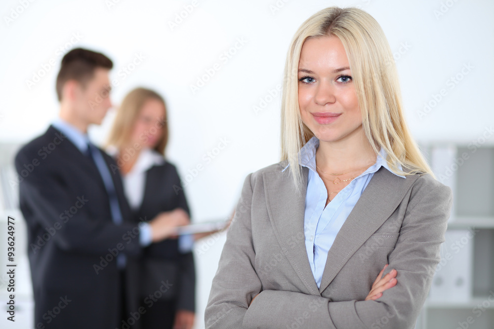 Pretty businesswoman in office with colleagues in the background Pretty businesswoman in office with colleagues in the background