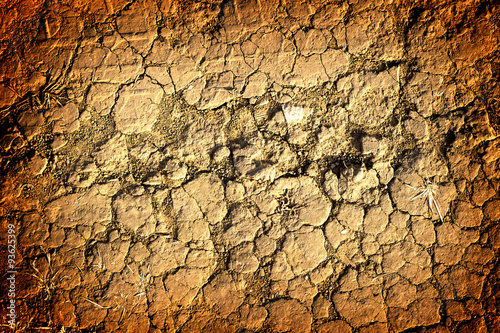 Texture of yellow withered earth with cracks high contrasted with vignetting effect