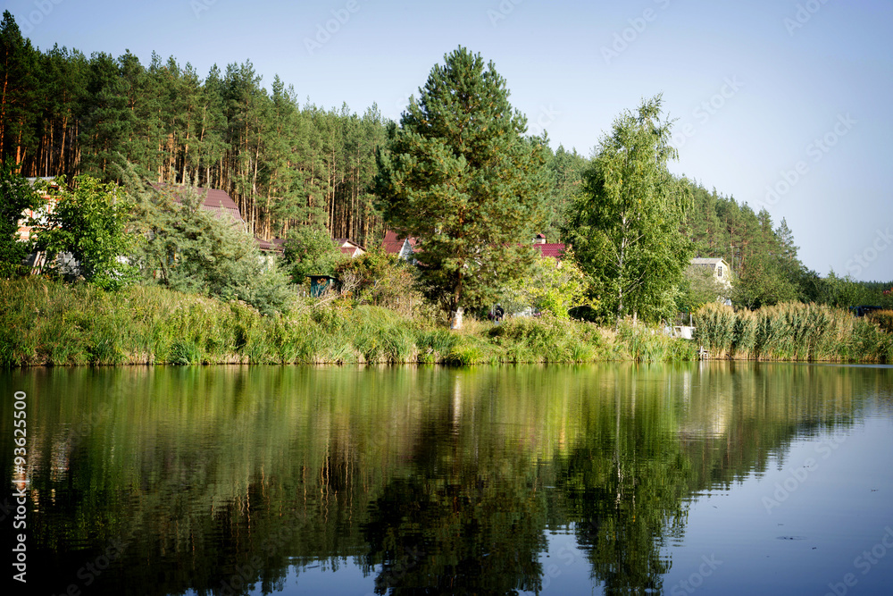 River house with reflections and blue sky near the forest high contrasted with vignetting effect