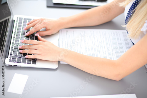 Close up of business woman hands typing on laptop computer, blue tie with polka dots