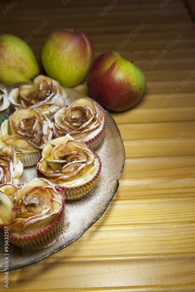 Baked apple pies in form of roses with cinnamon and cloves, decorated with natural organic apples on Murano glass plate, selective focus, space for text Baked apple pies in form of roses with cinnamon and cloves, decorated with natural organic apples on Murano glass plate, selective focus, space for text