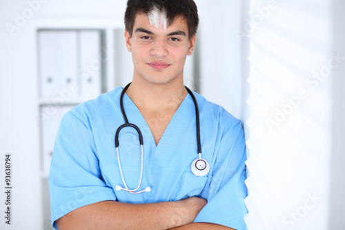 Portrait of unknown male surgeon doctor standing near the wall in hospital office