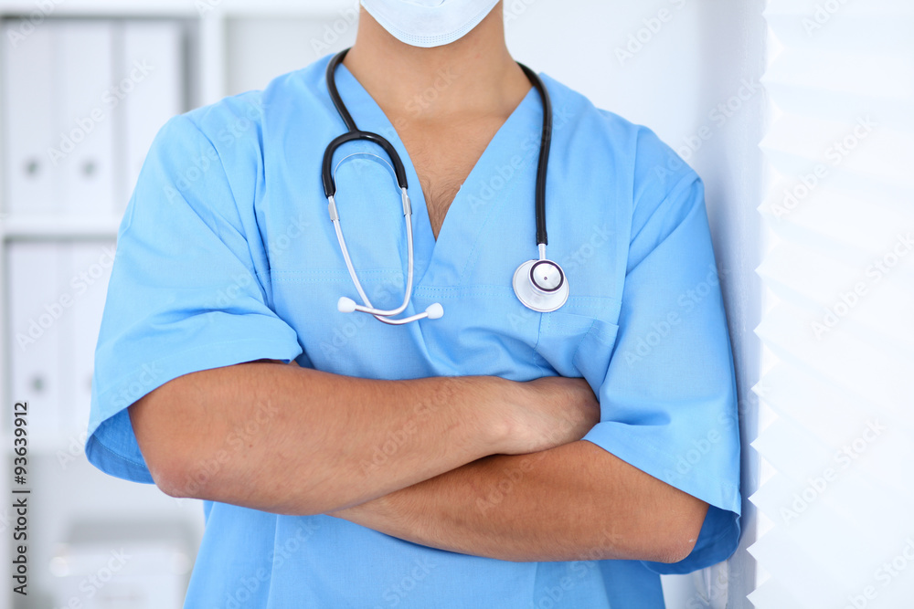 Portrait of unknown male surgeon doctor standing near the wall in hospital office Portrait of unknown male surgeon doctor standing near the wall in hospital office