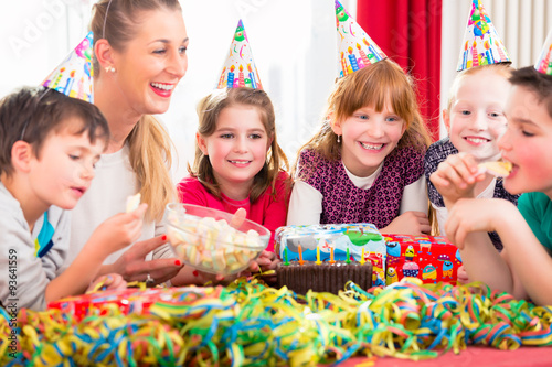 Children on birthday party nibbling candies