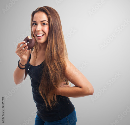 portrait of a young woman biting a chocolate donut