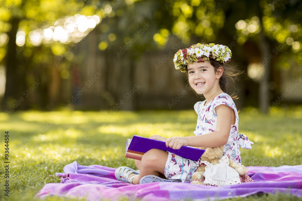 Fototapeta premium Little girl reading in the park