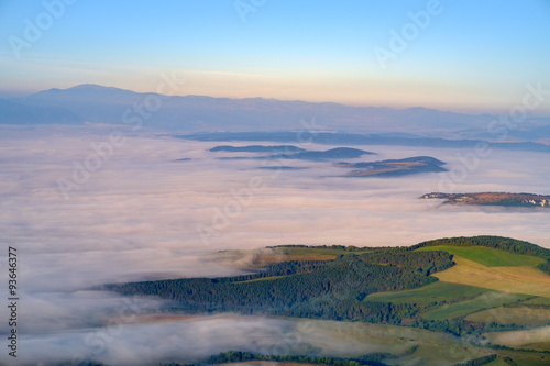 Beautiful landscape view of hills and meadows, mist and clouds