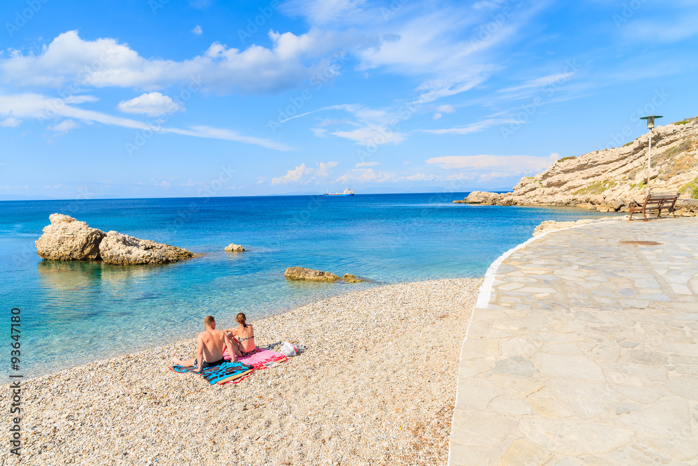 Couple of unidentified people relaxing on beautiful Kokkari beach, Samos island, Greece