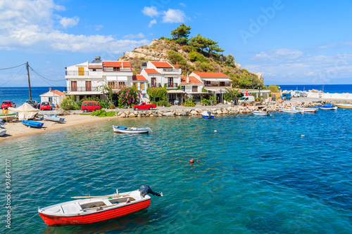 Fishing boat in Kokkari bay with colourful houses in background, Samos island, Greece