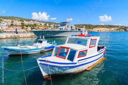 Typical colourful fishing boats with warship in background in Pythagorion port, Samos island, Greece