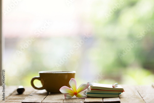 Notebook and cup with flower on wooden table