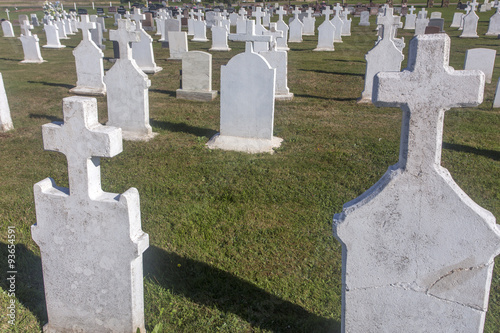 white concrete gravestones with crosses in cemetery of historical Notre-Dame-du-Mont-Carmel Church, Prince Edward Island