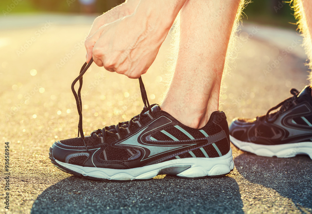 Naklejka premium Male runner tying his shoes